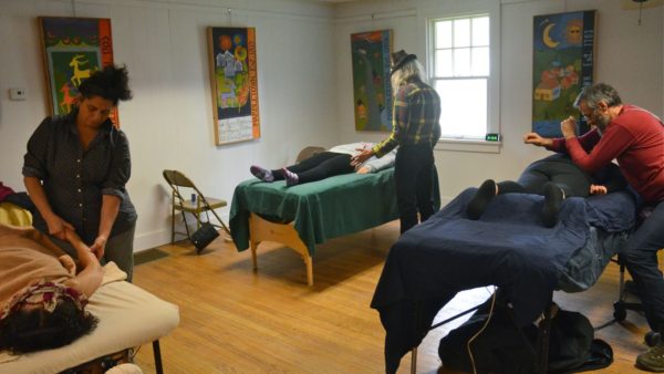 Massage therapists work on clients on three different massage tables at a clinic hosted by the Holistic Health Community.